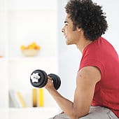 Young man exercising with weight indoor, side view